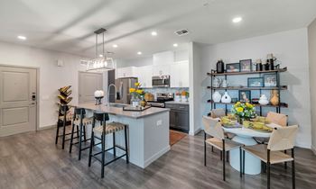 A kitchen and dining room area with a table and chairs and a refrigerator